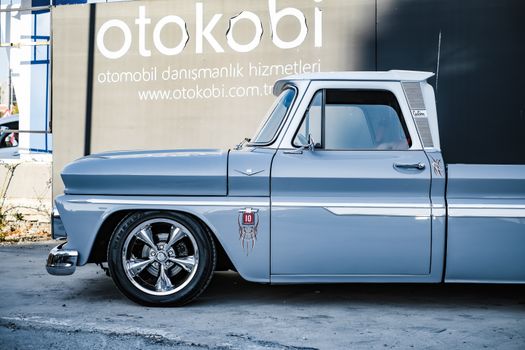 Side view of a classic blue pickup truck parked in front of an Otokobi sign.