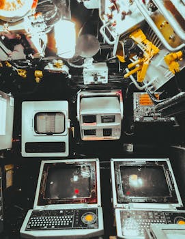 Interior view of a vintage control room featuring retro computer equipment and switches.