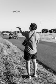 Black and white photo of a man flying a drone in rural Tomas Jofre, Argentina.