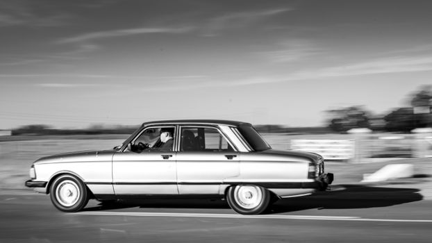 Black and white photo of a vintage car in motion on a rural road in Tomas Jofre, Argentina.