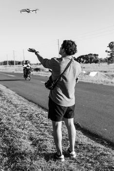 A man controls a drone by a countryside road in Tomas Jofre, Argentina.