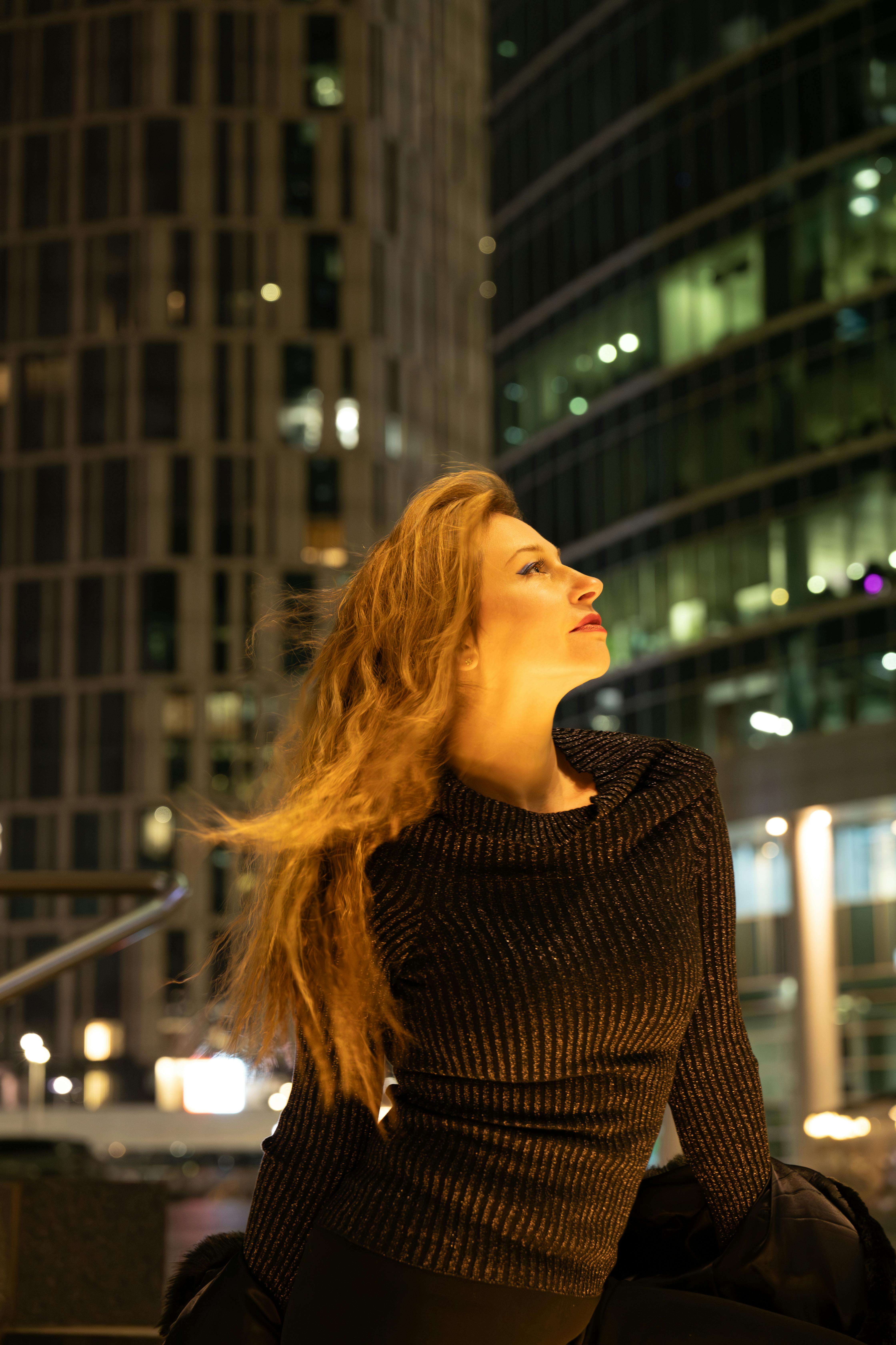 Profile portrait of a woman in a cityscape at night, elegant and modern.