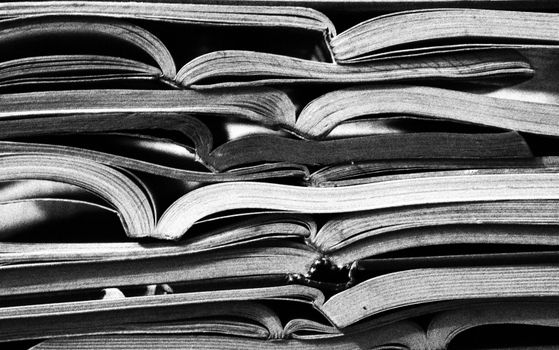 Monochrome image of stacked open books, showcasing texture and patterns in literature.