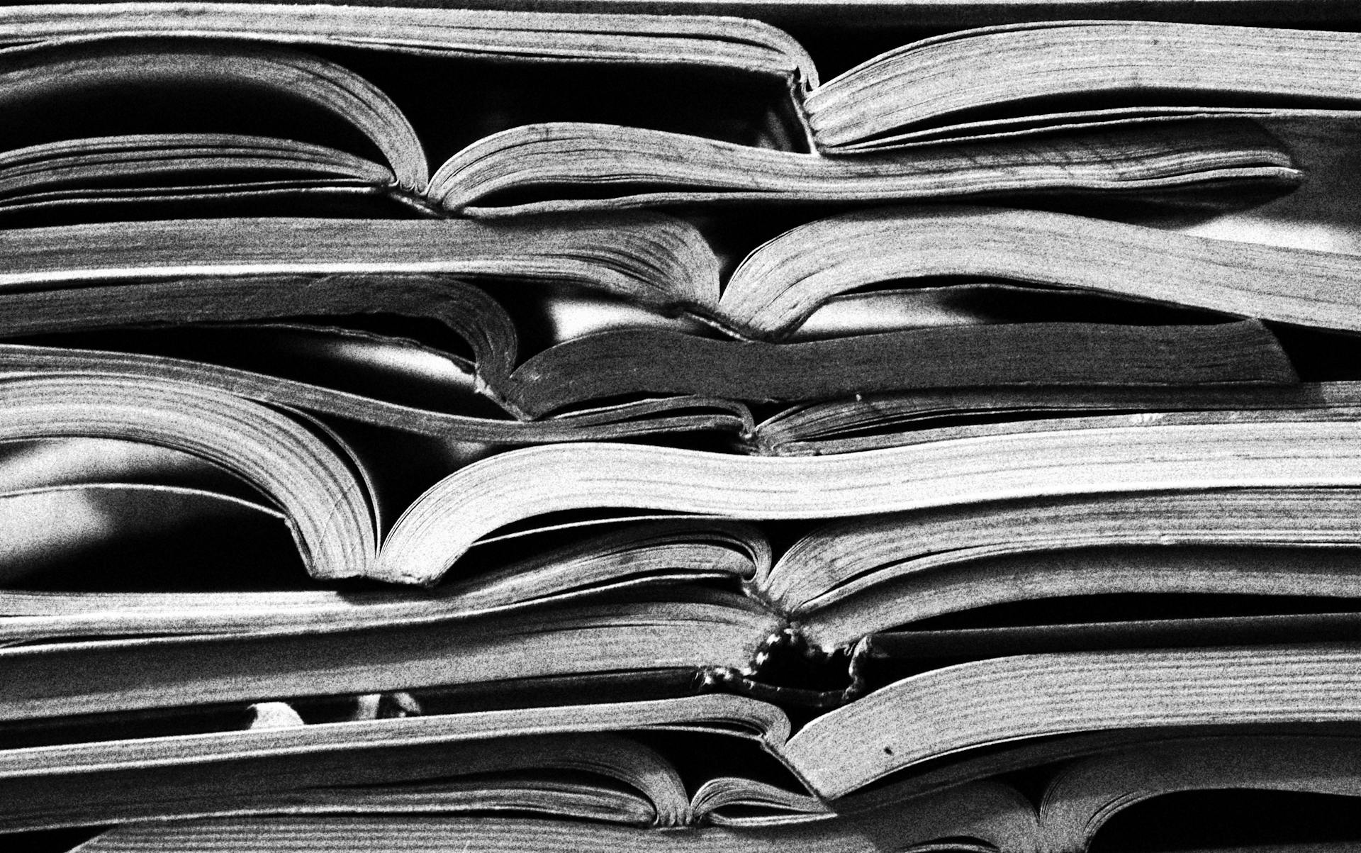Monochrome image of stacked open books, showcasing texture and patterns in literature.