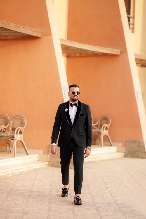 Free Stylish man in a tuxedo walks confidently in a sunny outdoor setting. Stock Photo
