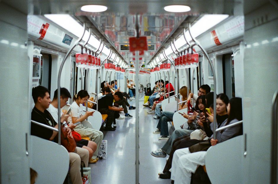 Commuter looking at phone screen in evening train with city lights passing by