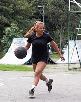 Woman playing basketball on an outdoor court, showcasing athleticism and energy.
