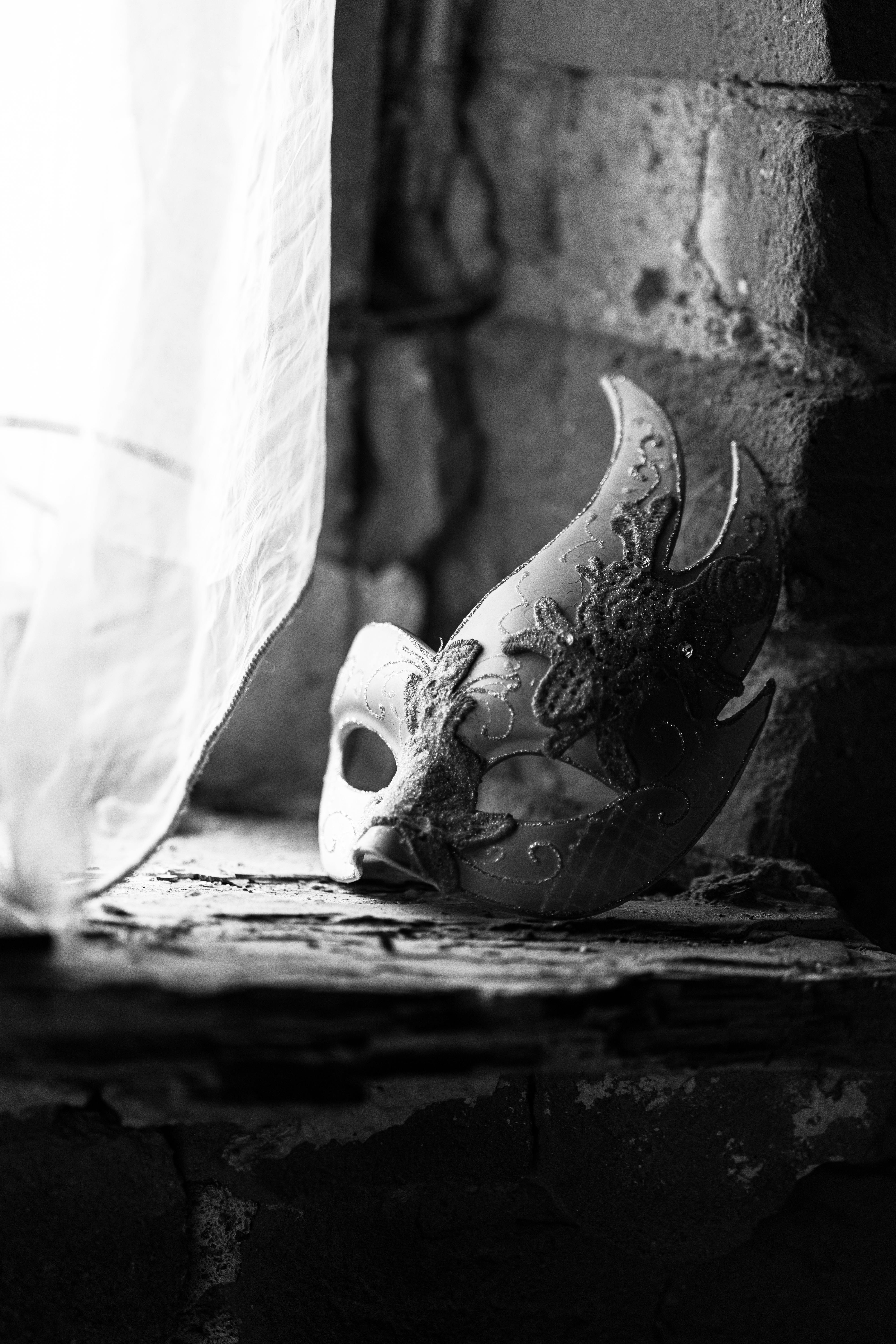 Free Black and white photo of a decorative Venetian mask on a rustic windowsill, exuding a sense of mystery and elegance. Stock Photo
