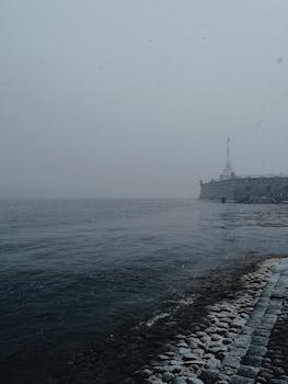 朦胧的海岸景色与远处的建筑，共同营造出一种宁静而又略带忧郁的氛围