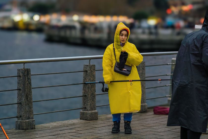 A long yellow hooded raincoat worn with the hood up on a waterfront