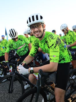 Cyclists in vibrant jerseys prepare at a road race event, smiling and ready.