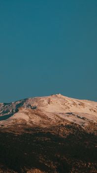 Scenic view of a snow-covered mountain peak under a clear blue sky, perfect for travel and nature themes.
