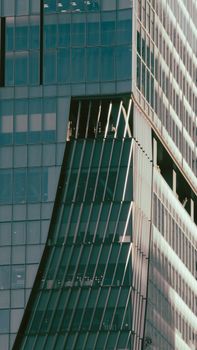Close-up of modern skyscraper with unique architectural features and glass facade.