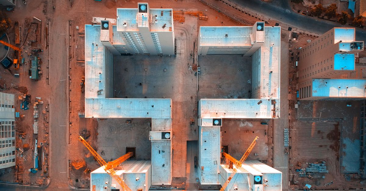 Drone aerial view of a construction site in Mendoza, Argentina with cranes and buildings.