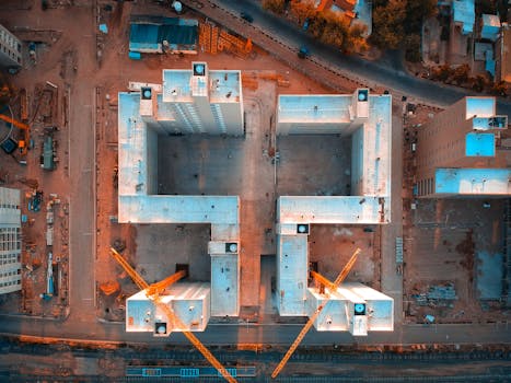 Drone aerial view of a construction site in Mendoza, Argentina with cranes and buildings.