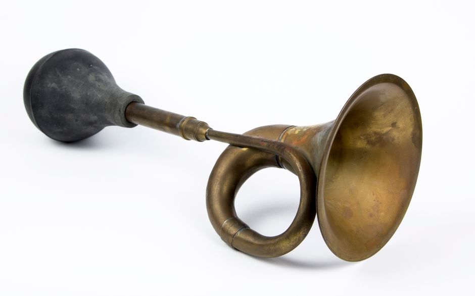 A vintage brass horn lying on a white surface, showcasing its antique design and patina.
