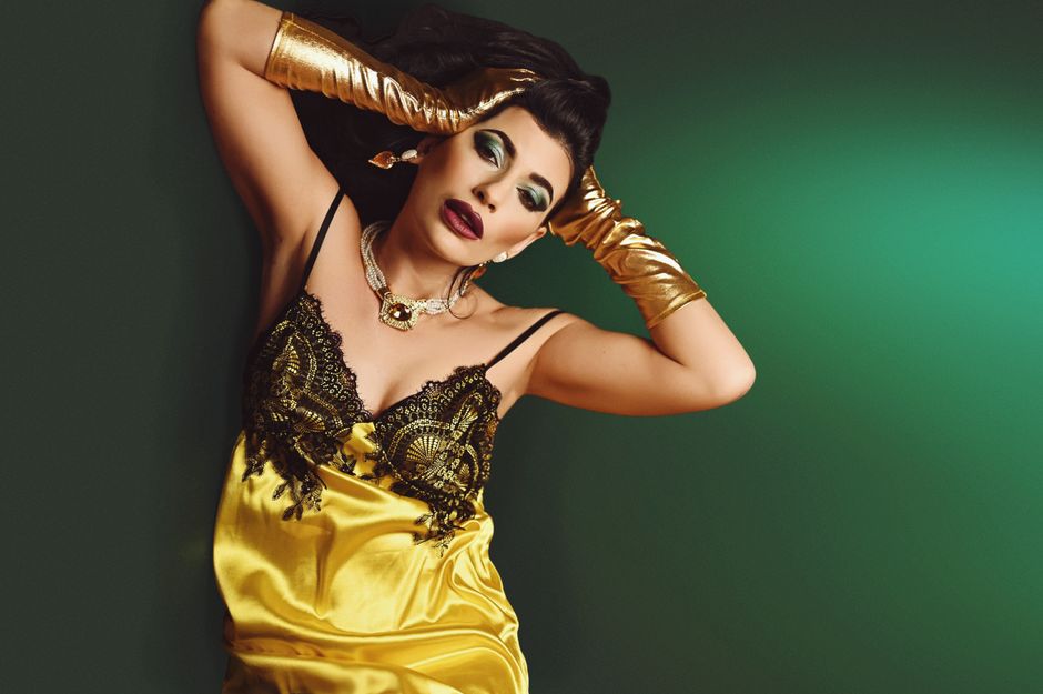 Portrait of a stylish woman in a golden satin dress with luxurious jewelry and makeup, exuding elegance.