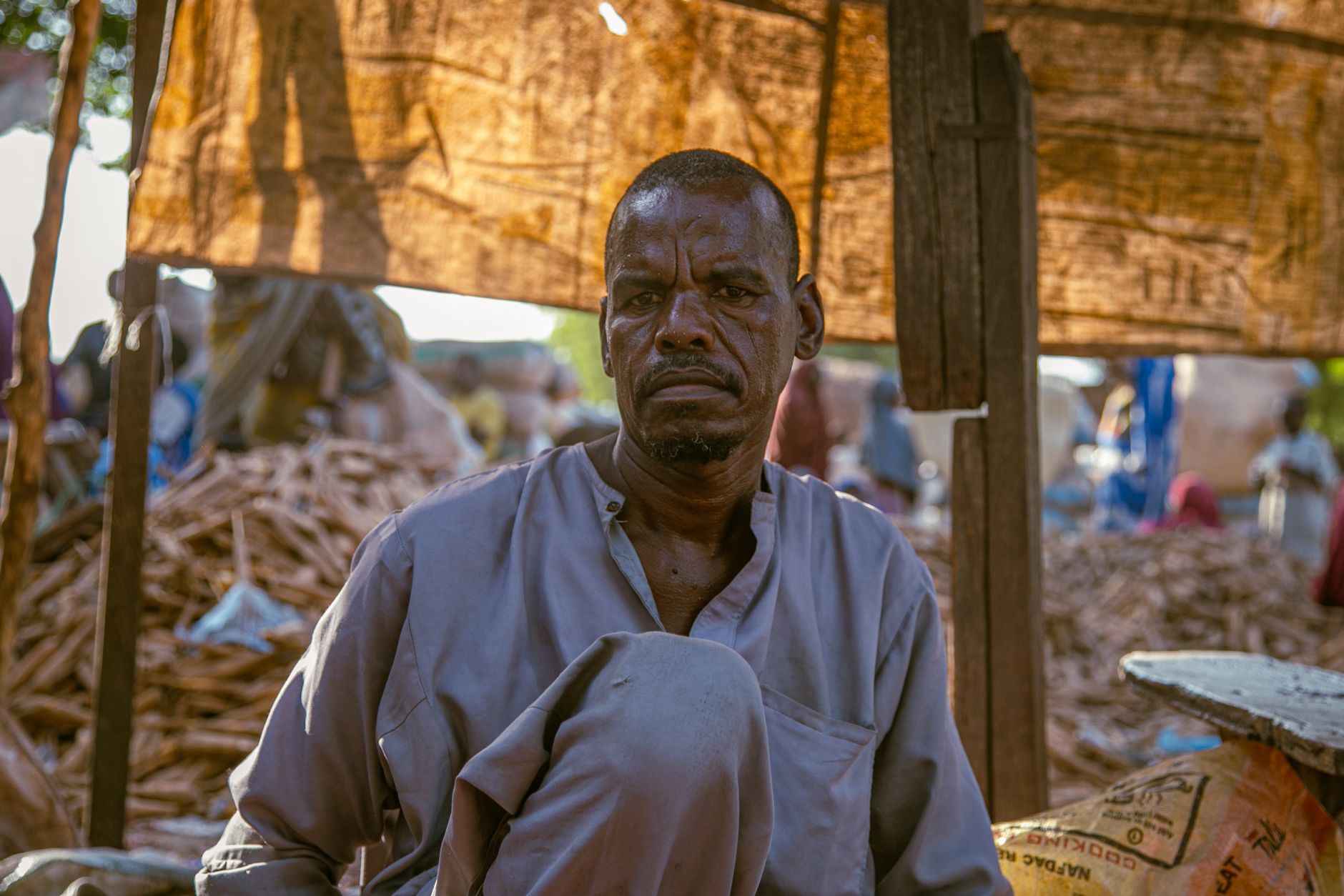 Portrait of a Nigerian market vendor in Maiduguri, showcasing local attire and market ambiance.