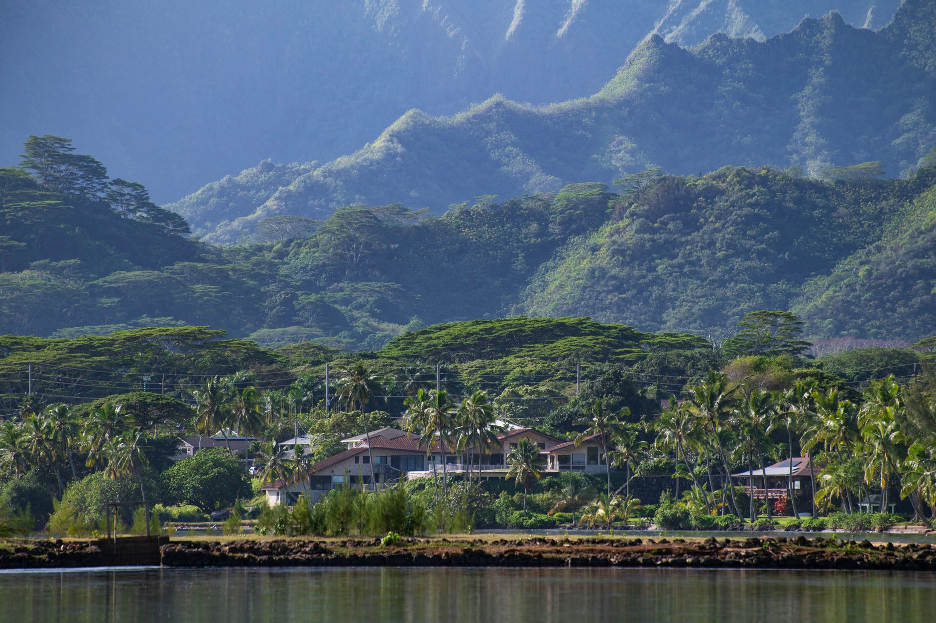 Charming village nestled in tropical greenery with majestic mountains in the background.