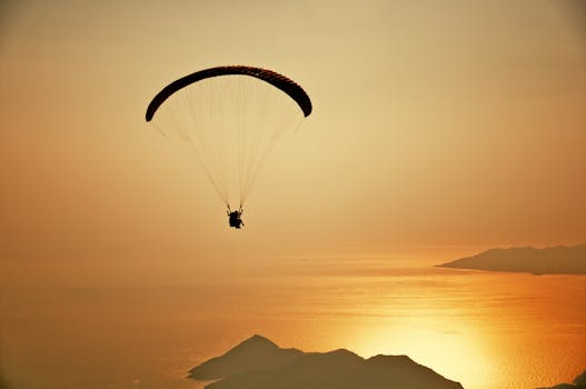 A silhouette of a paraglider flying over the stunning Ölüdeniz at sunset.