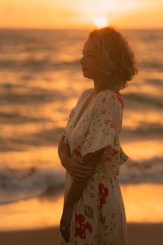 A serene silhouette of a woman in a floral dress by the ocean during a calming sunset.