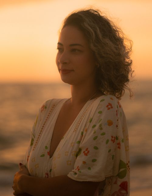 Free A serene beach portrait of a woman enjoying a sunset in a floral dress. Stock Photo