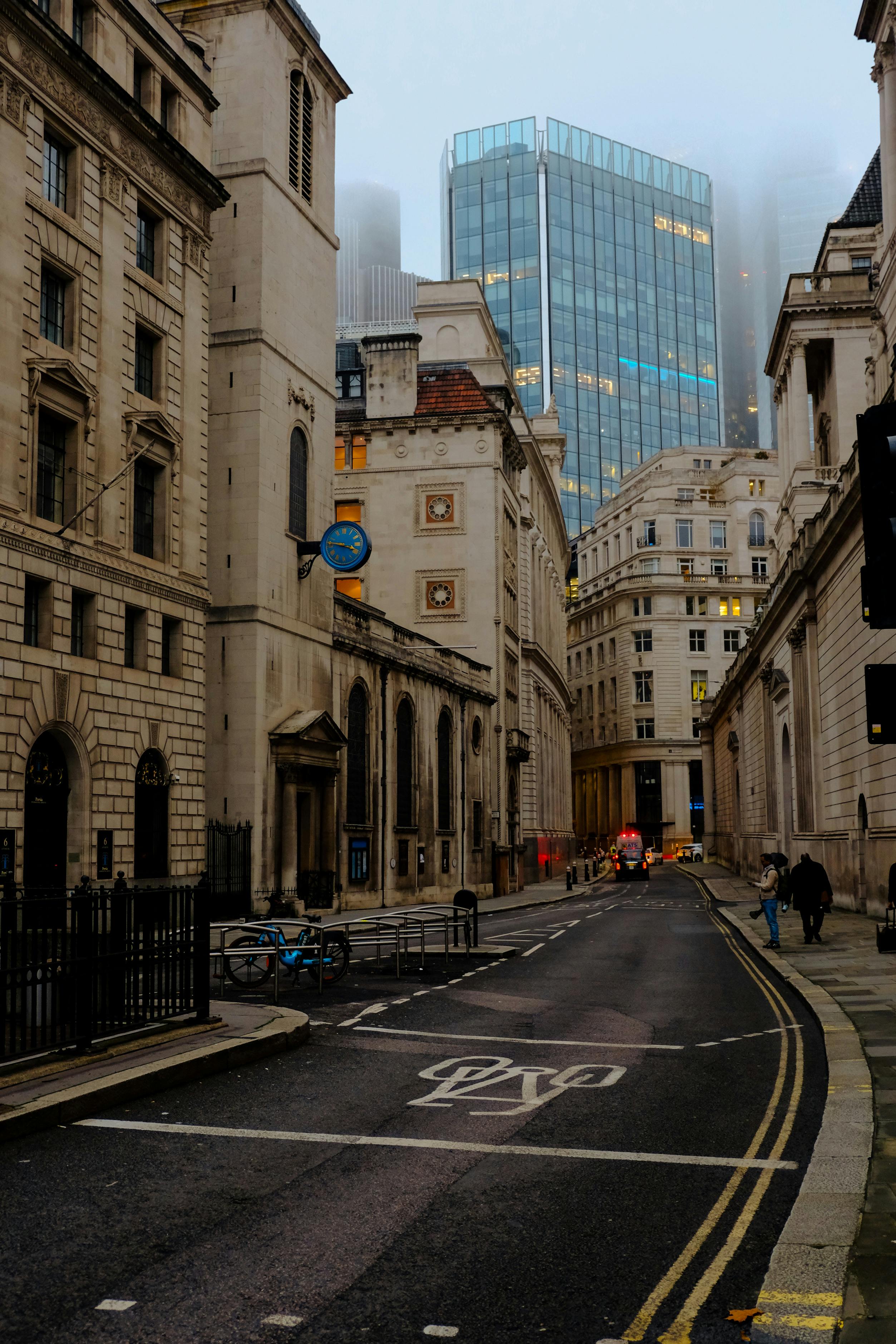 Historic architecture and modern skyscrapers in London's foggy city center street.