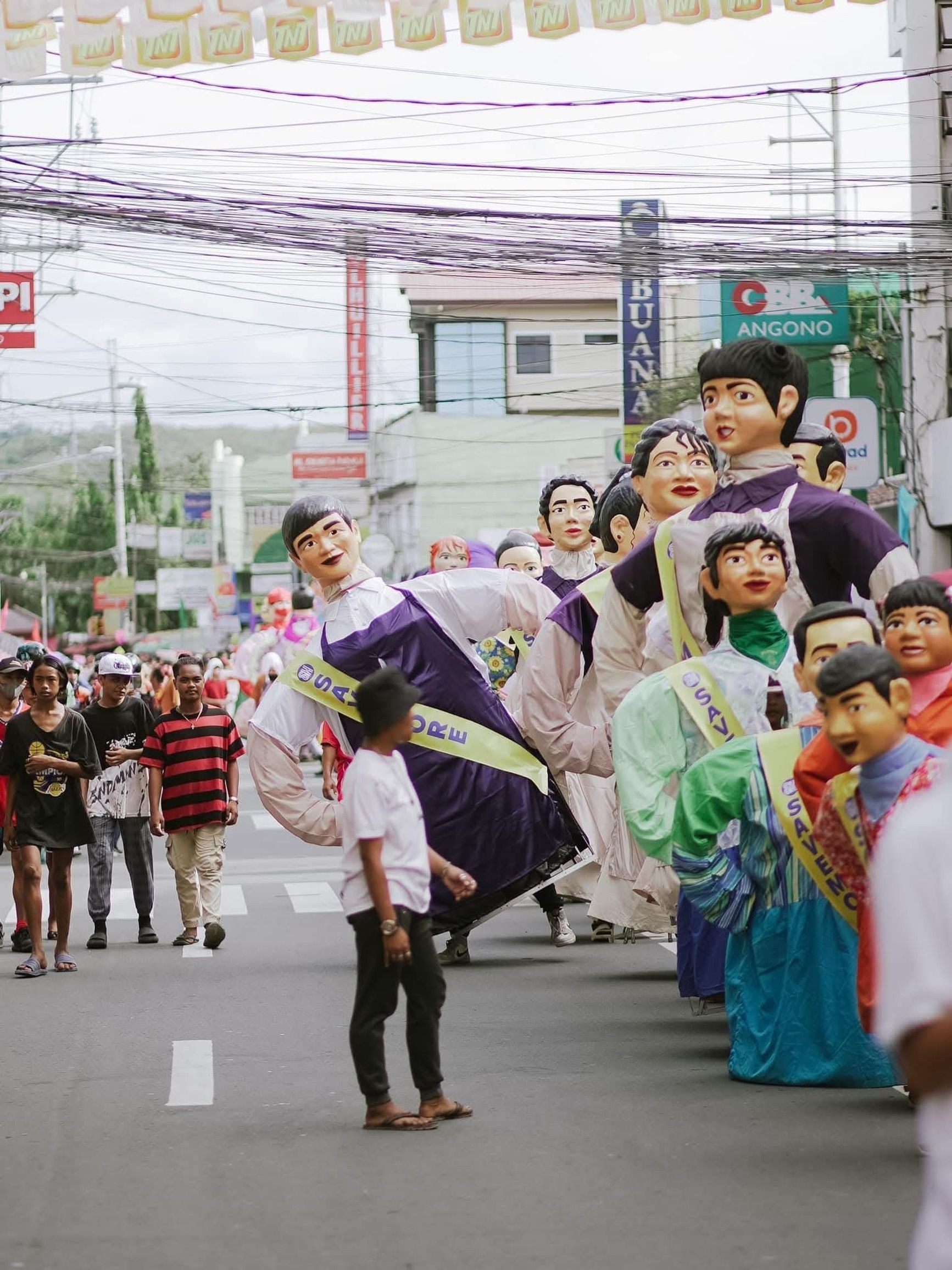 Vibrant street festival featuring giant puppets parading through a lively city street.