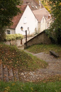 A picturesque cobblestone path in a quaint European village with autumn foliage.