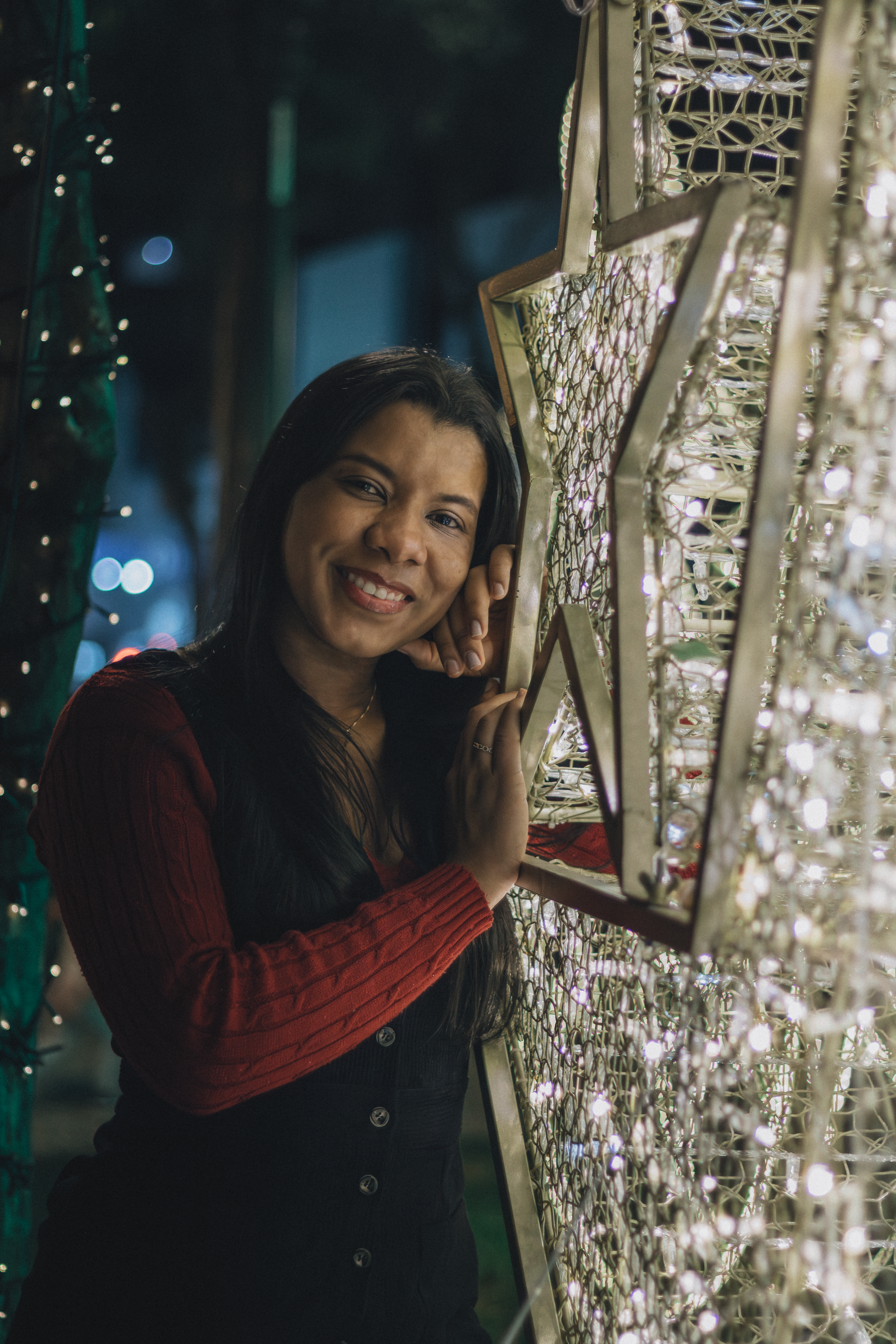 Happy woman posing with star-shaped lights in a festive night scene, capturing holiday spirit.