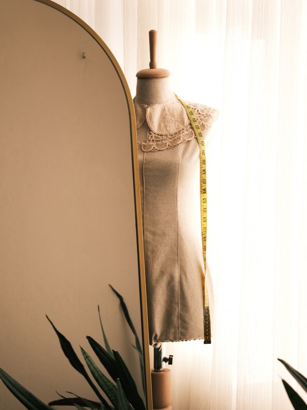Dress stand with a lace collar and a measuring tape