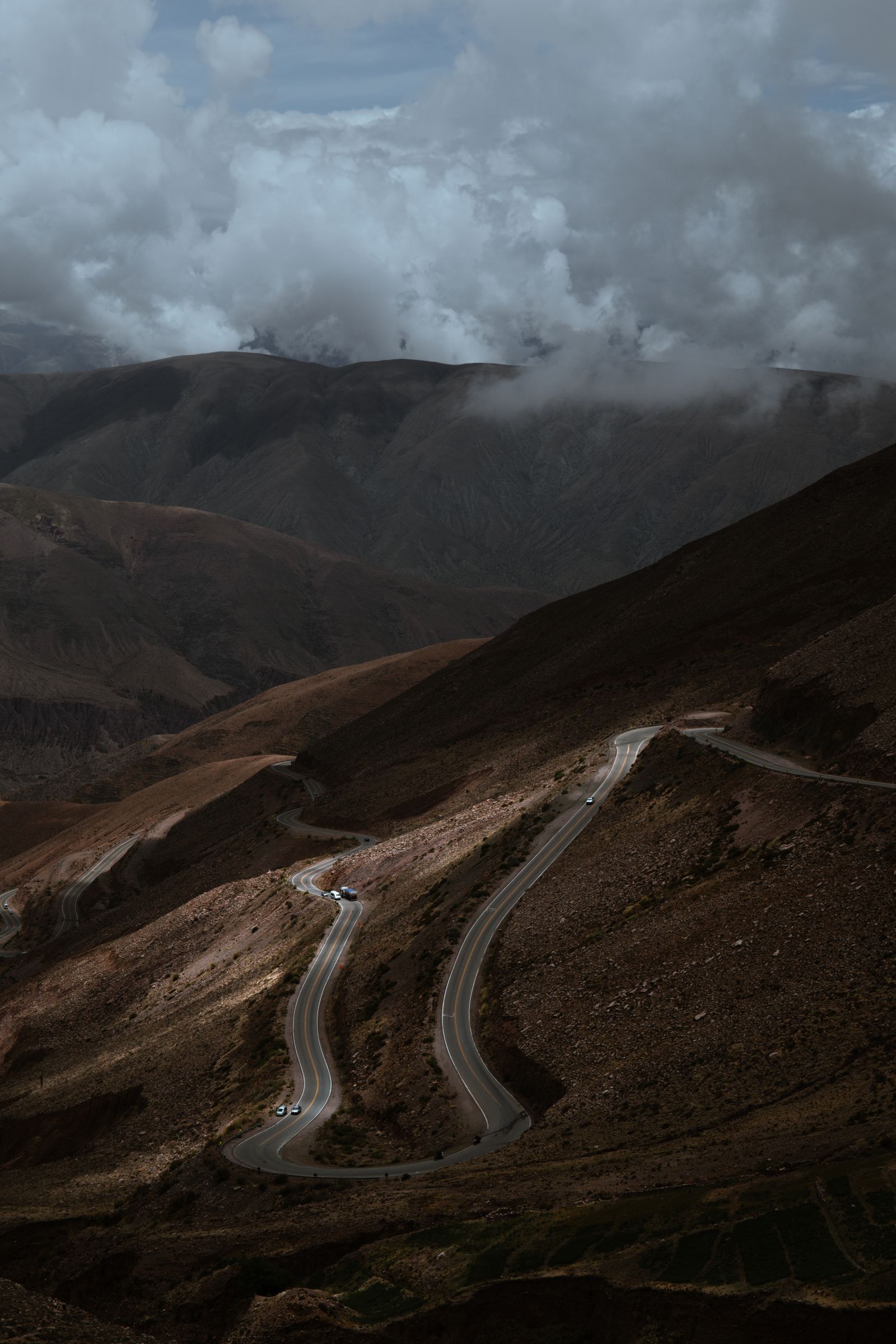 Winding mountain road with dramatic clouds showing why slow riding is safer in Ha Giang