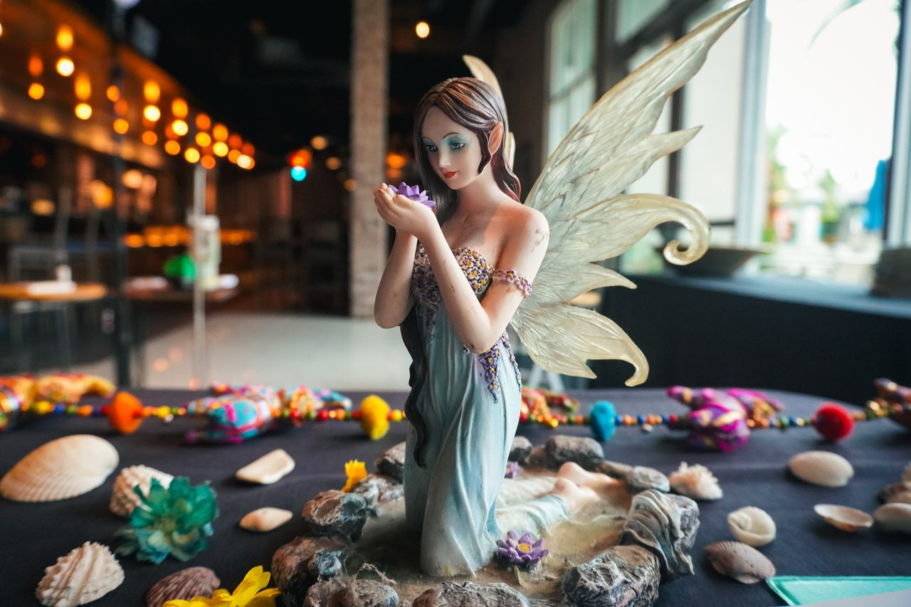 a delicate fairy figurine with wings surrounded by seashells and vibra
