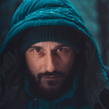 Close-up portrait of a man wearing a hooded jacket in a cold outdoor setting, capturing winter vibes.