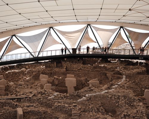 Free Archeological ruins of Göbekli Tepe under canopy, with tourists observing. Stock Photo
