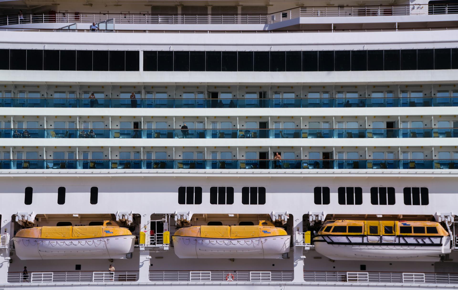 Close-up view of a modern cruise ship showing lifeboats and passenger cabins.