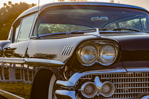Free Close-up of a vintage Chevrolet car's front with gleaming chrome details captured at sunset. Stock Photo