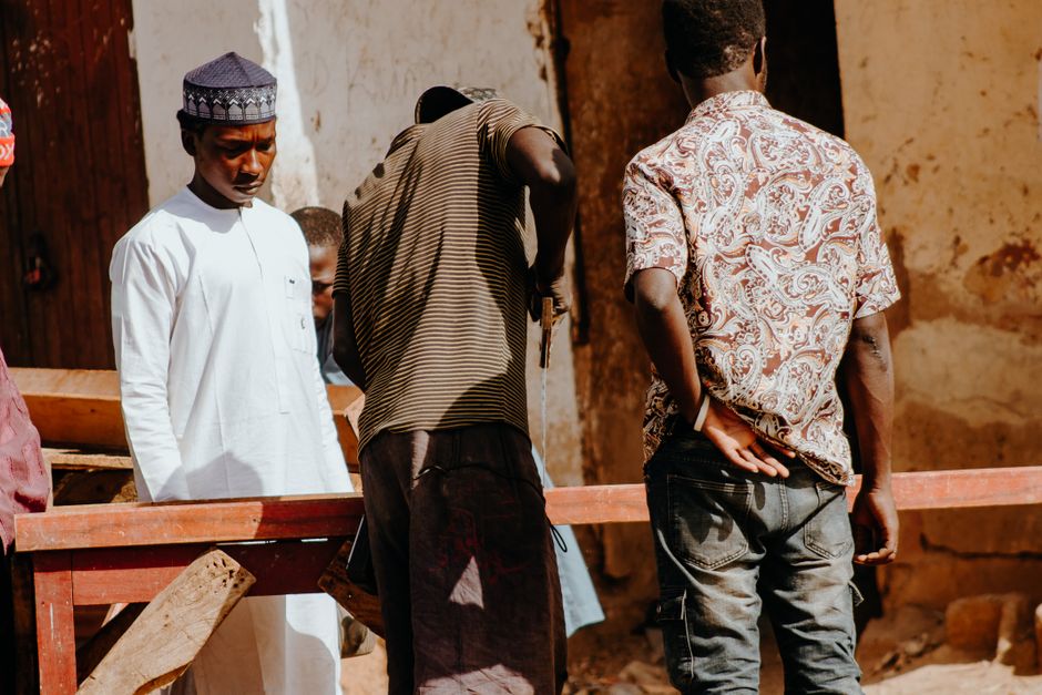 A group of men collaborating on a project outdoors in bright daylight.