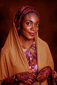 Graceful woman in traditional attire with henna designs posing with a smile.