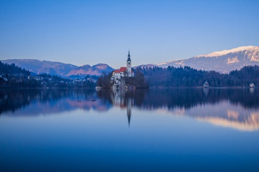 Captivating view of Lake Bled with the iconic church and serene reflections at dawn in Slovenia.