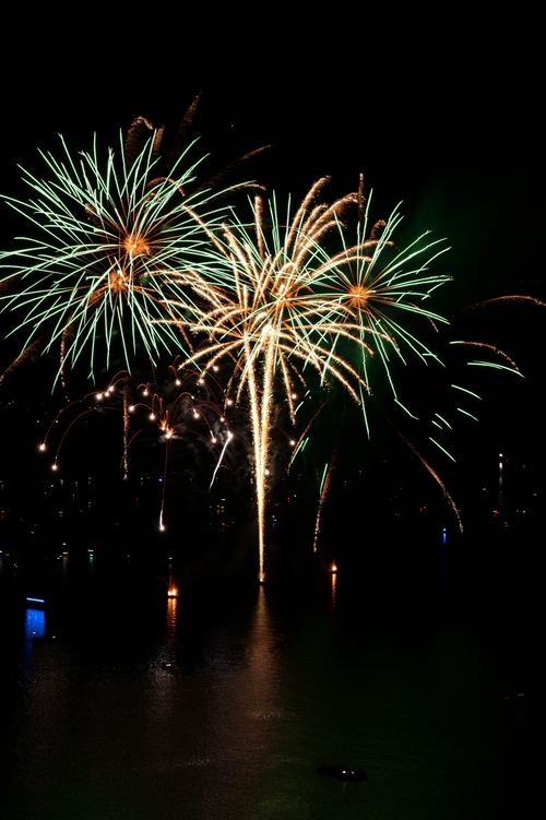 Free Vibrant fireworks light up the night sky over a water body, creating a stunning reflection. Stock Photo