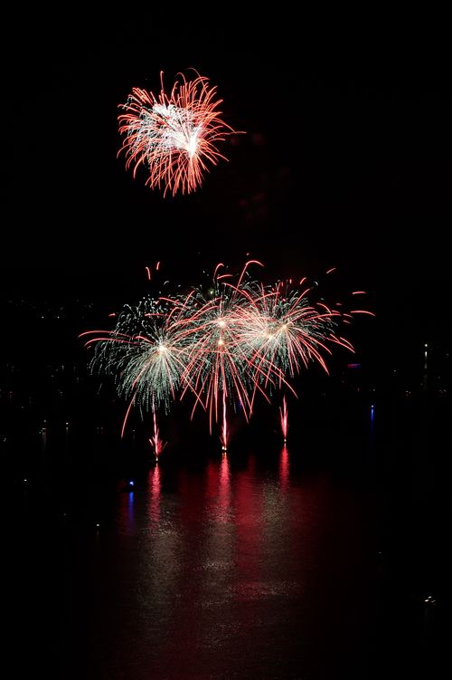 Free Colorful fireworks lighting up the night sky over a calm water body, reflecting beautifully. Stock Photo