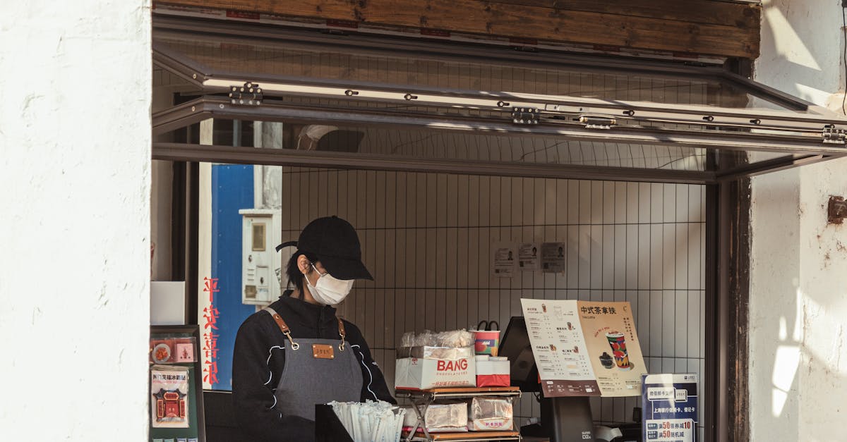 Photo by 女子 正真 A worker behind the counter of an outdoor cafe kiosk, preparing orders.