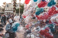 主题公园热闹的街道上飘着五彩缤纷的米奇和米妮气球