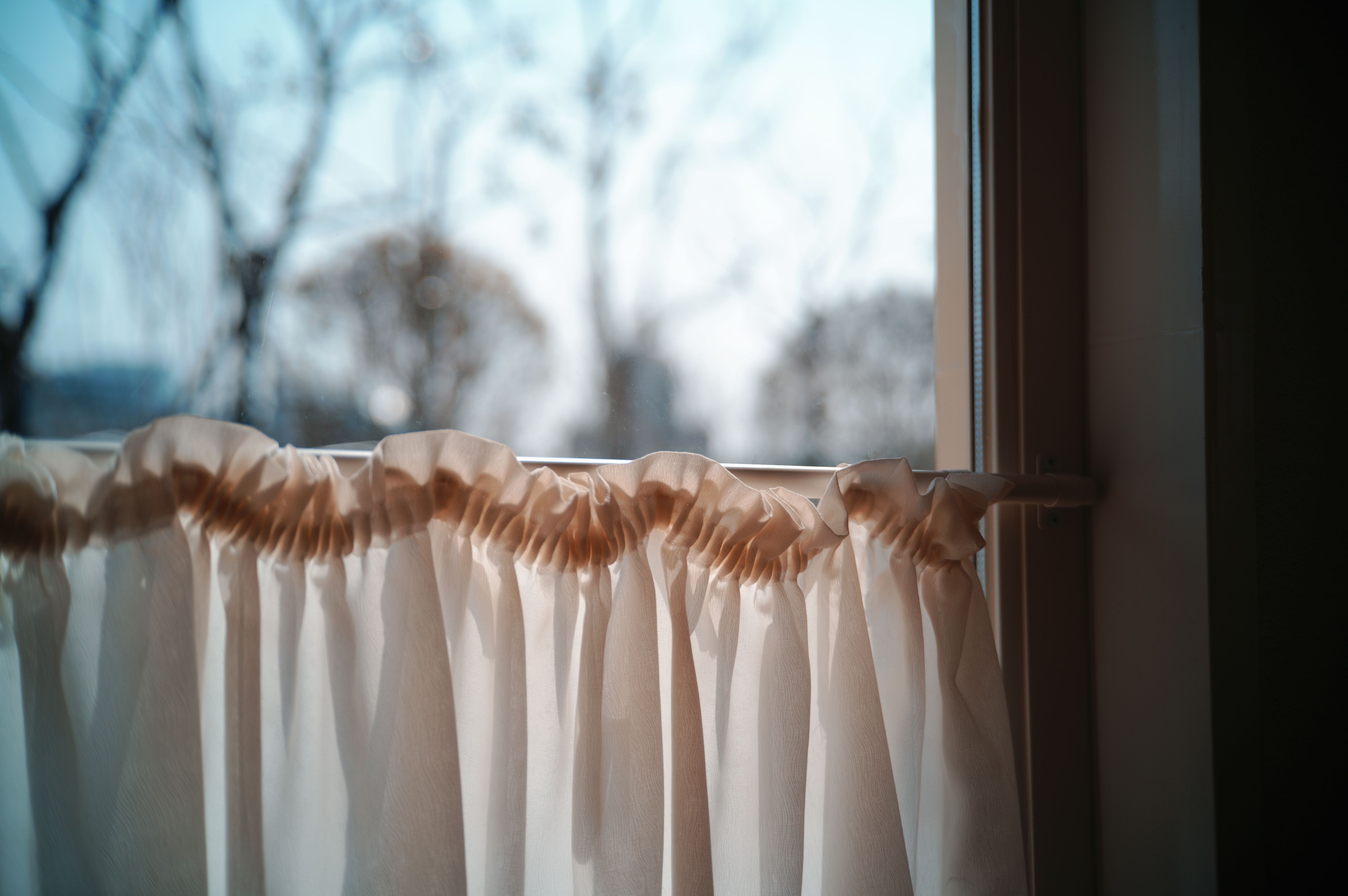 Cozy and serene atmosphere with sunlight streaming through white curtains. Perfect for a peaceful setting.