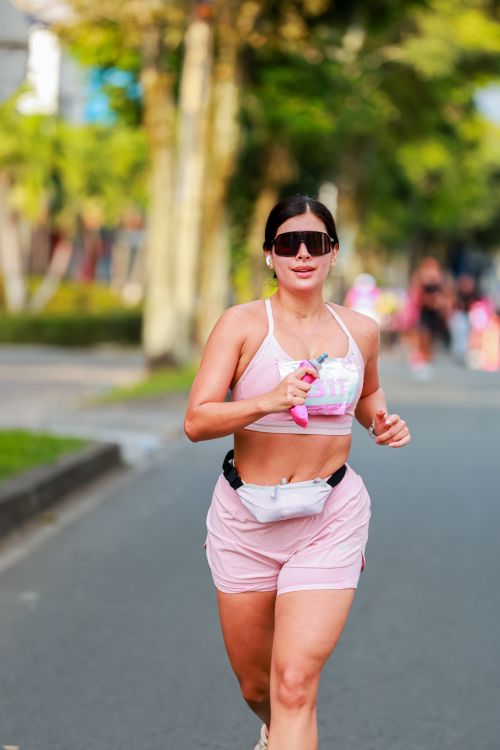 Free Energetic woman jogging on a sunny day in vibrant pink activewear, showcasing fitness and lifestyle. Stock Photo