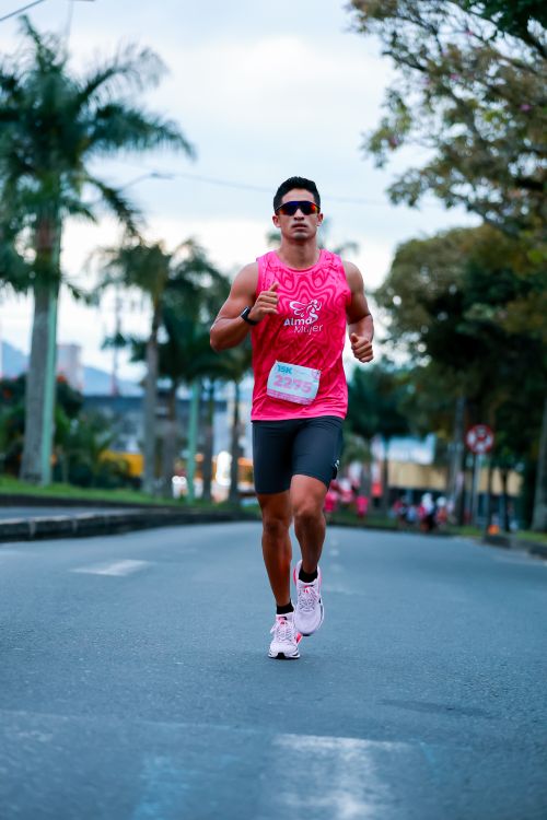 Free Fit man running in a marathon wearing a pink tank top on a clear day outdoors. Stock Photo