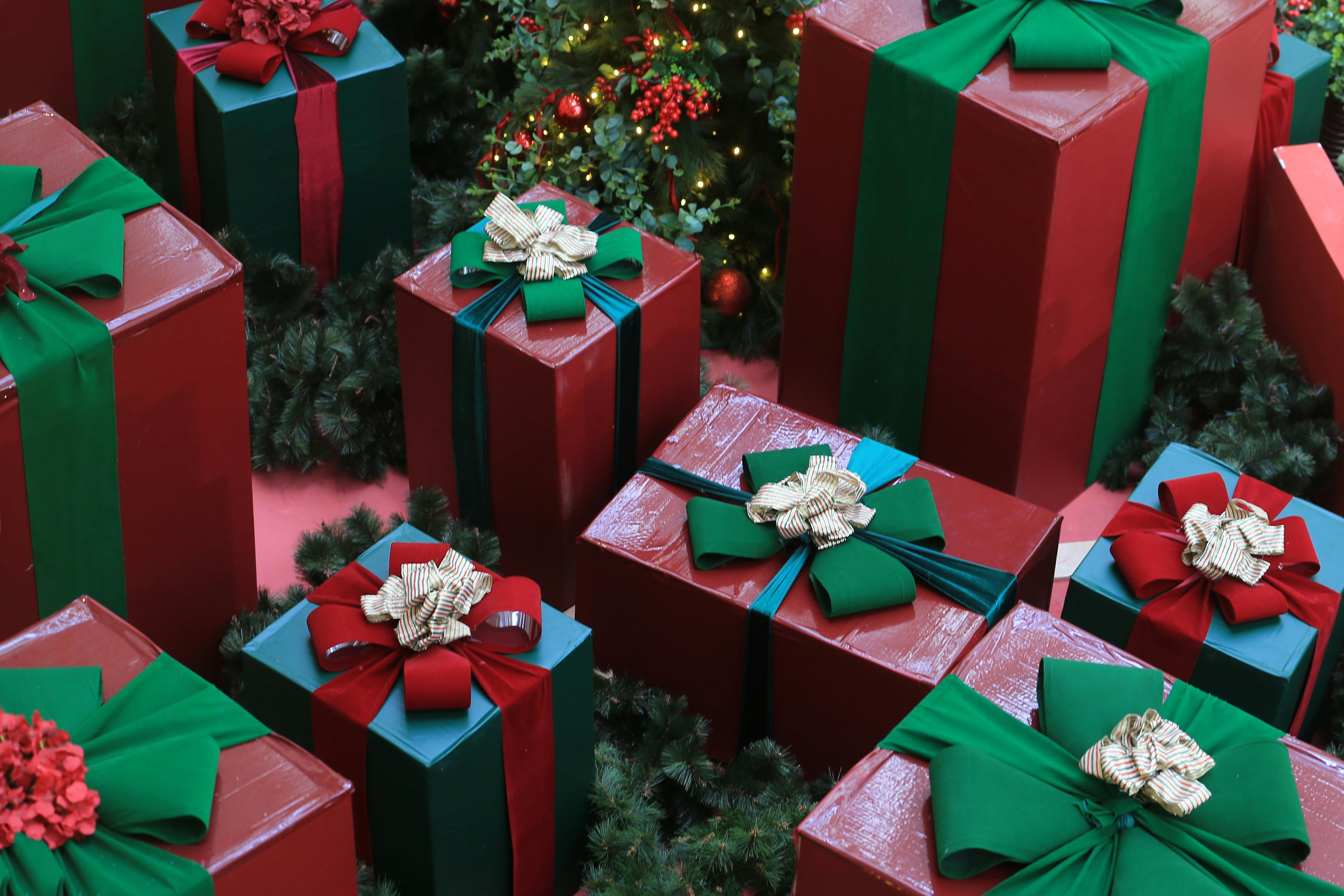 Aerial view of red gift boxes wrapped with green and red ribbons, surrounded by Christmas foliage.