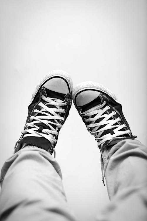 Grayscale Photography of Person Wearing Sneakers