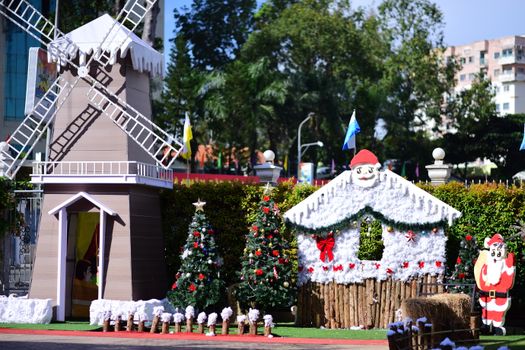 Charming outdoor Christmas display featuring a festive windmill, Santa Claus decorations, and Christmas trees.